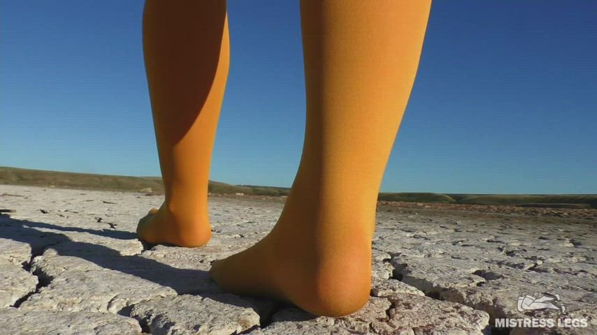 Walking in yellow pantyhose by dried up lake