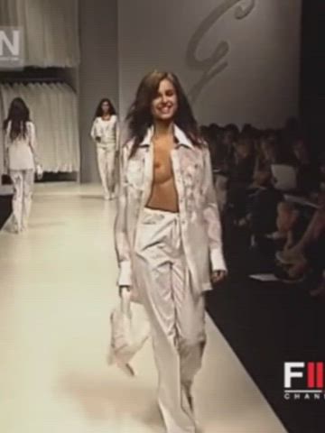 Runway model smiles happily as one of her tits slowly pops out of the open shirt