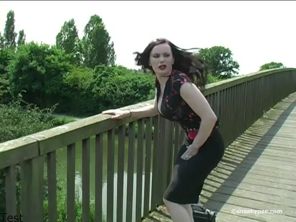 Raven-haired girl pissing on the bridge
