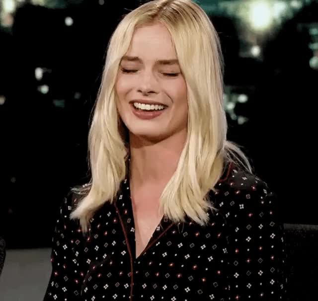 Margot Robbie pretending to be embarrassed after the audience is shows clips of her