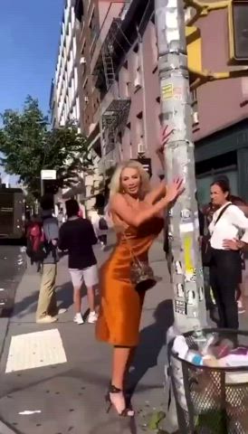 Video: blonde woman with large implants wearing orange cowl neck dress dancing &amp;