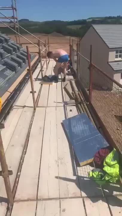 Builder uses a saw to cut his trousers into shorts