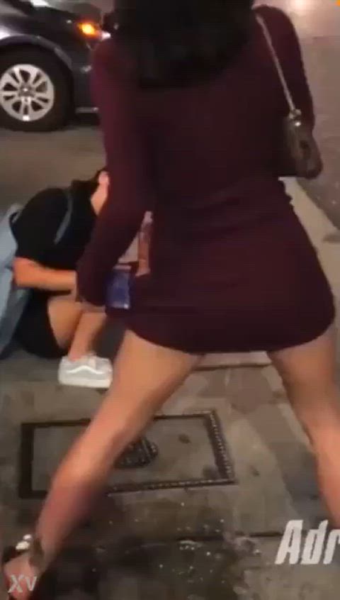 Two girls pissing on the side of a street