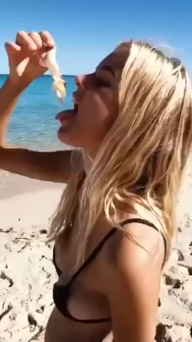 Sexy Australian Girl in tiny black bikini eating crayfish on the beach