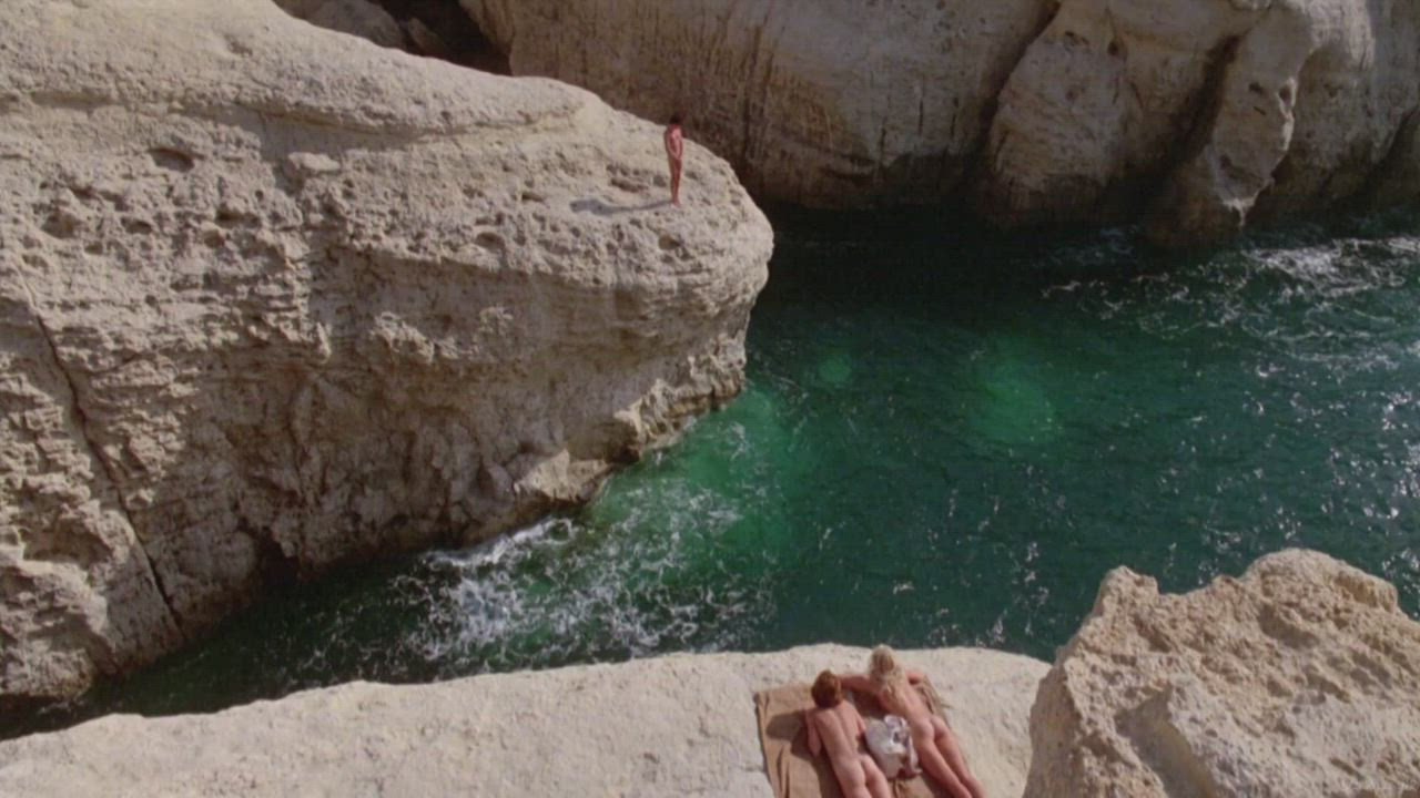 Ladies sunbathe, watching Michael jump off the cliff (Daryl Hannah &amp; Valérie