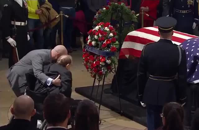 95-year-old former Senator Bob Dole helped out of wheelchair to give a final salute