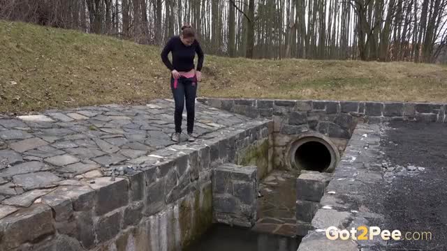 Brunette sprays her piss over the edge of a public drainage pipe - Watch full video