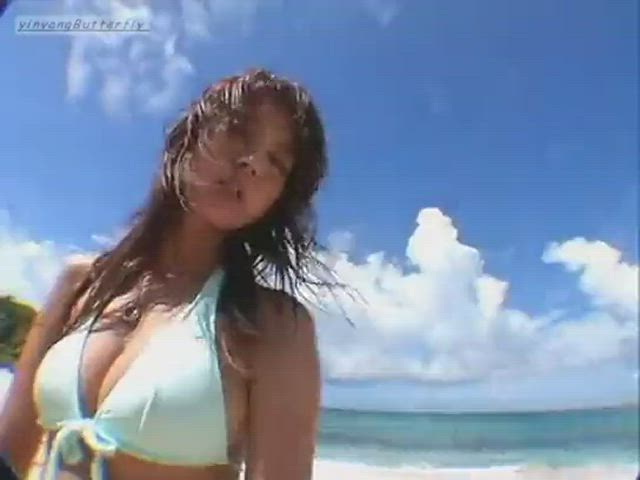 Asian girl unties her blue bikini top at the beach