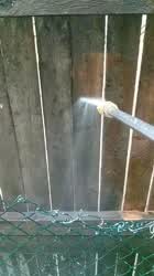 Super slow motion of a high pressure washer giving a dilapidated fence it's first
