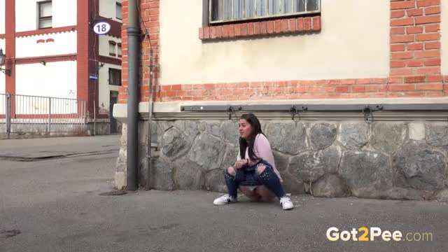 A shy and desperate European girl pissing in front of a building - Watch the full